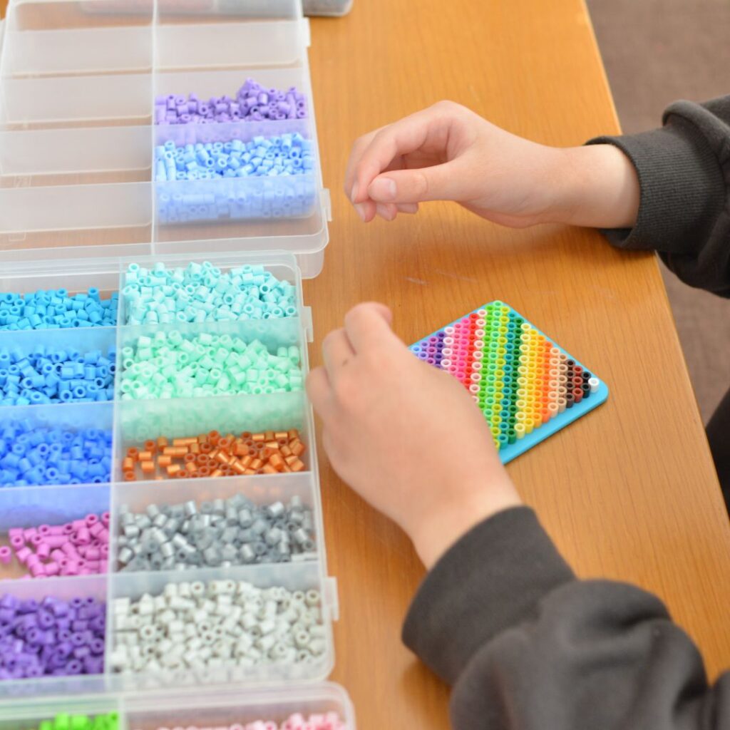 子どもがアイロンビーズケースから色を選びながら作品を作っている様子