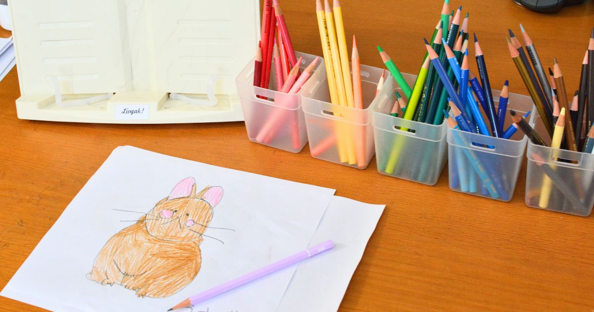 ダイソーのカップに立てた色鉛筆を使って子どもがお絵かきしている様子