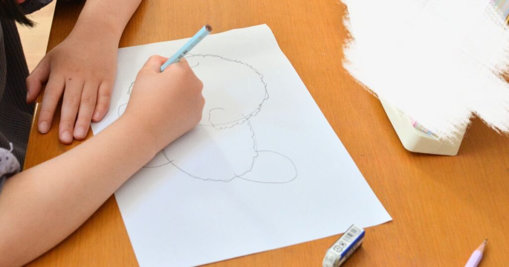 子どもが鉛筆でイラストを描いている写真
